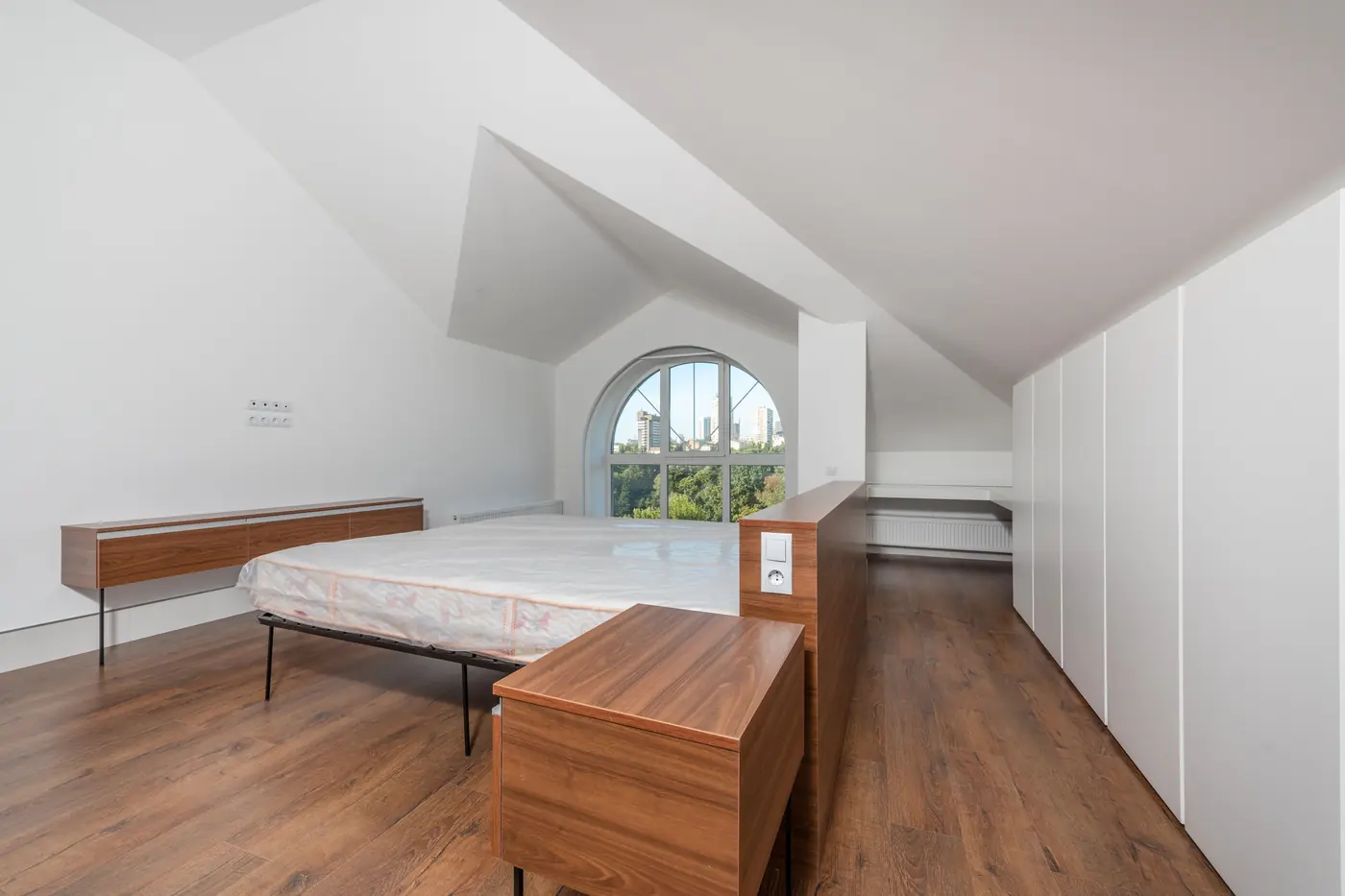 Chambre sous combles avec plafond en pente et lit contre le mur bas