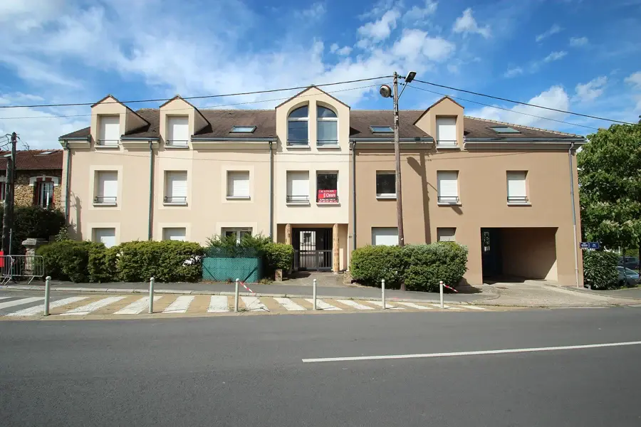 Petit immeuble résidentiel de deux étages avec un panneau d'agence à louer à une fenêtre, en bord de rue