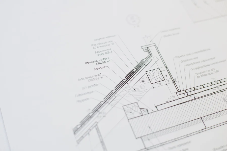 Plan d'architecte d'un logement posé sur une table, avec règle et crayon