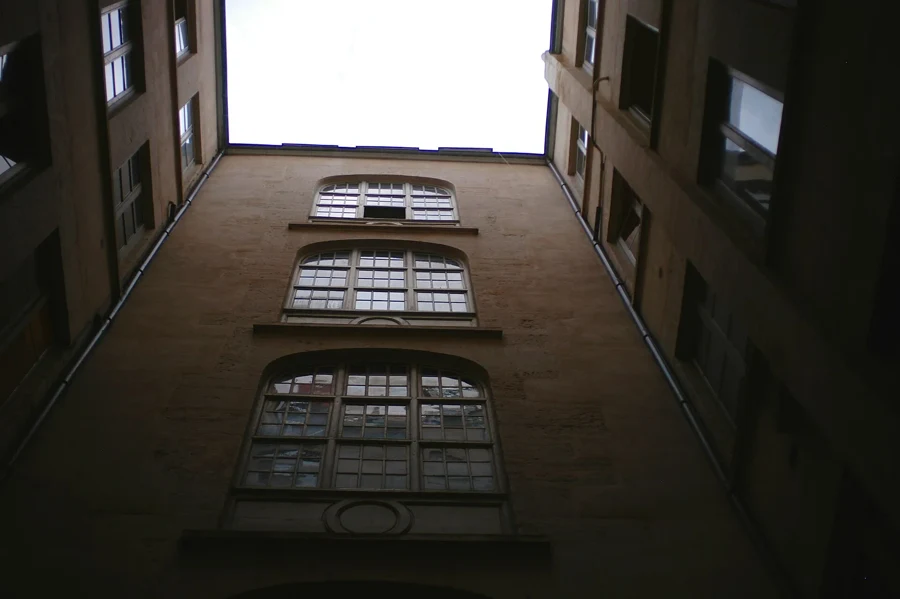 Cour d’un immeuble ancien vue d’en bas, avec ses fenêtres et ses façades