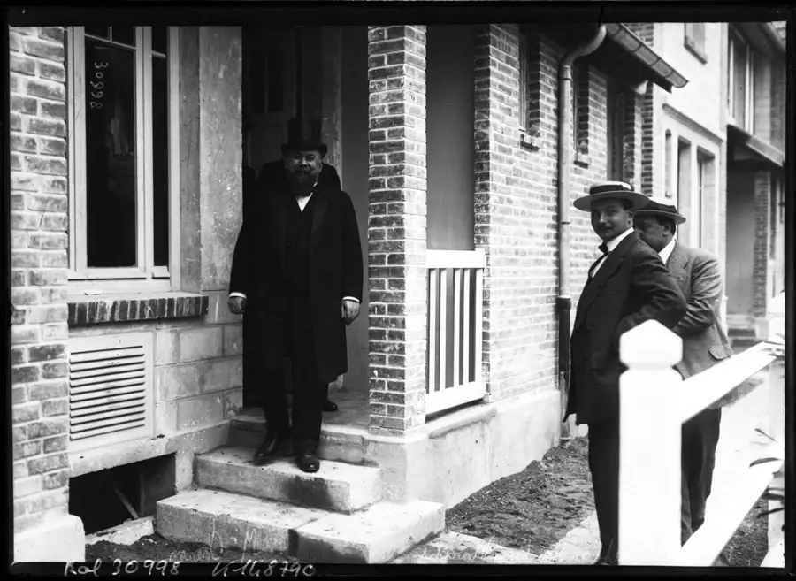 Inauguration d'habitations à bon marché au début du XXe siècle, maisons de brique et visiteurs en chapeau sur le perron